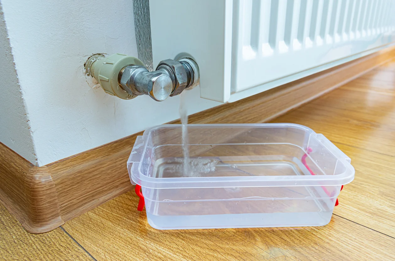 An image of a broken pipe that is leaking water in a Tupperware container symbolizing water intrusion and property losses from burst pipe claims handled by Trident Law HQ