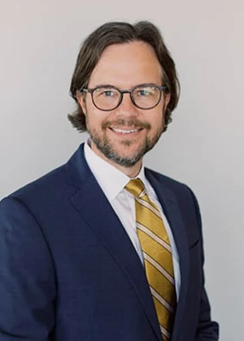 Formal studio portrait of Jason Shamblin, co-counsel with Trident Law HQ, with a neutral solid background.