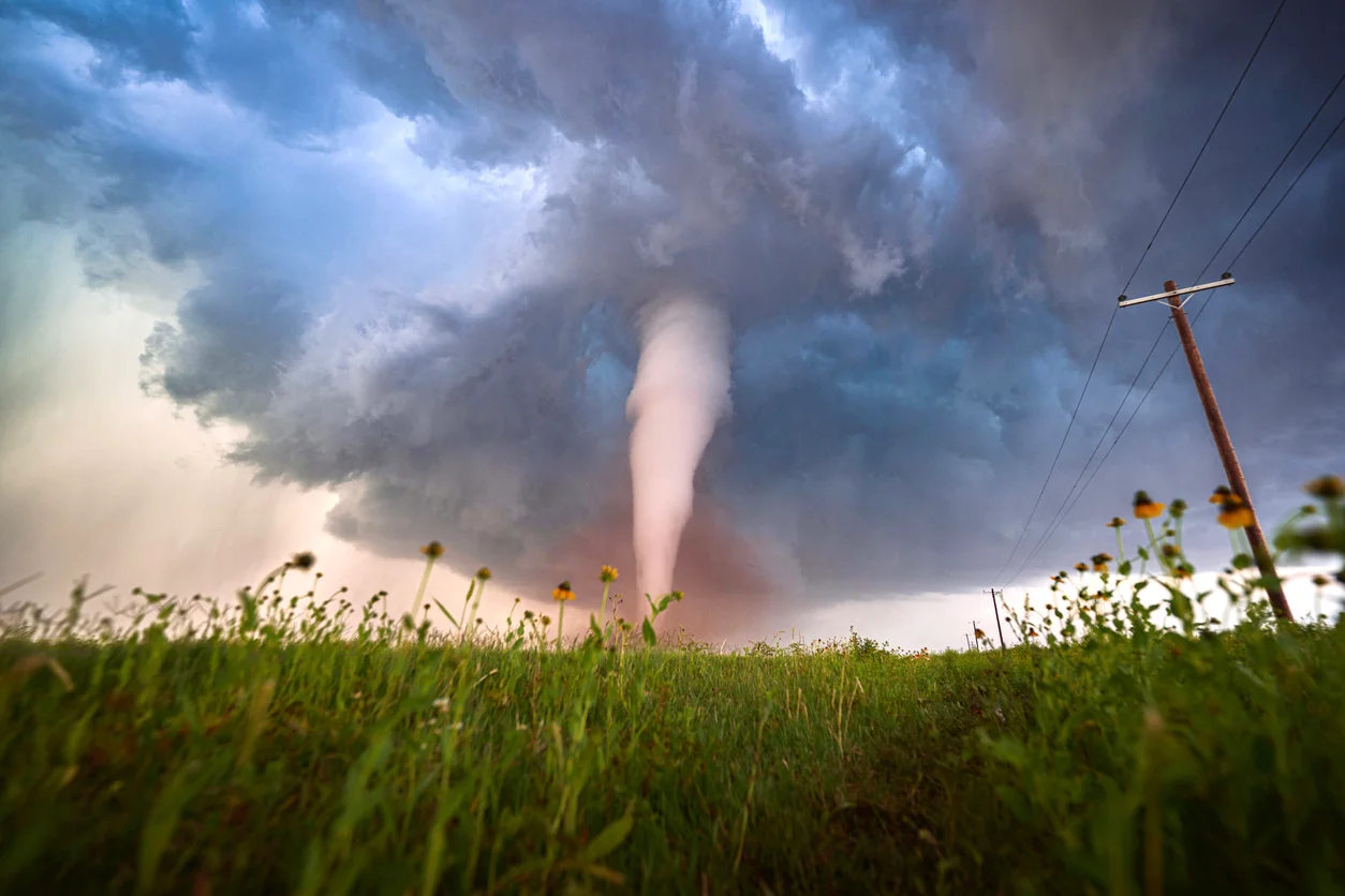 An image of a large tornado covering a large grassy area illustrating violent storm destruction and tornado damage claims litigated by Trident Law HQ
