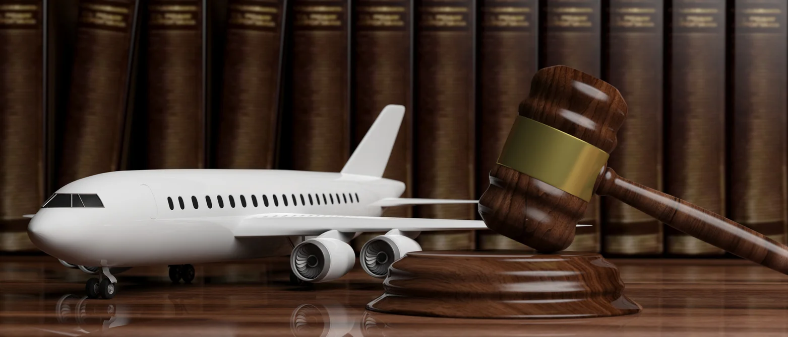 An image of a miniature airplane on a wood desk next to a gavel to represent aviation accident lawyers from Trident Law HQ