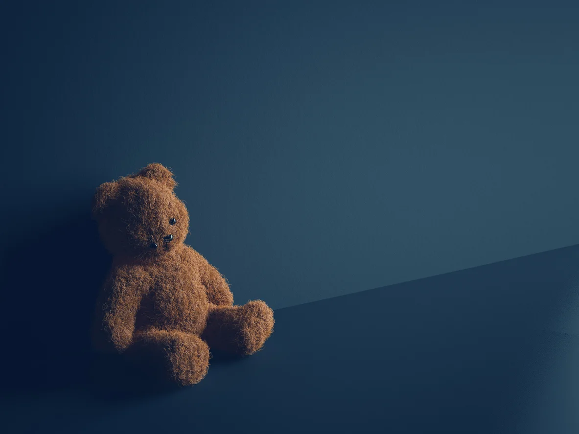 A small worn teddy bear against a blue background symbolizing the protection of children and child sexual abuse legal actions taken by Trident Law HQ