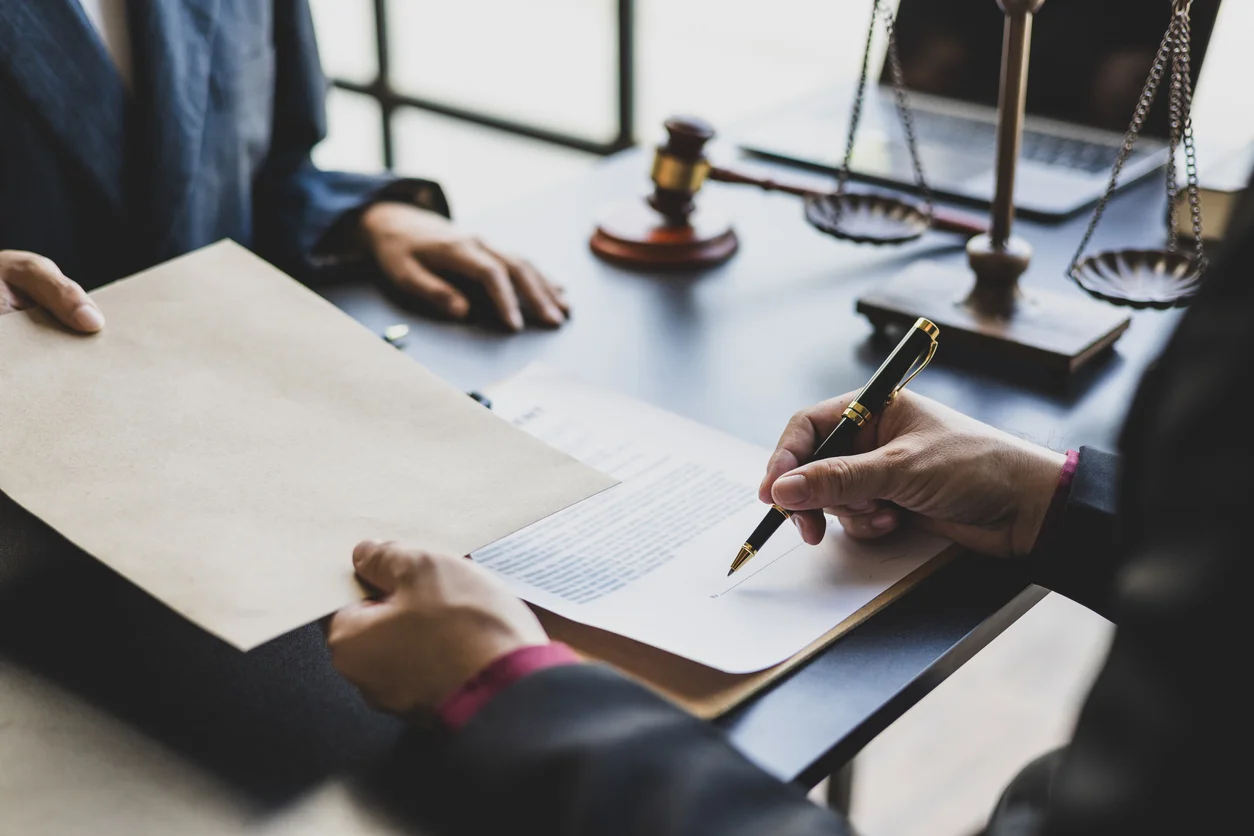 Corporate disputes and high-stakes commercial litigation managed by Trident Law HQ, shown here through a photo of a pair of hands signing a business contract while someone else looks on 