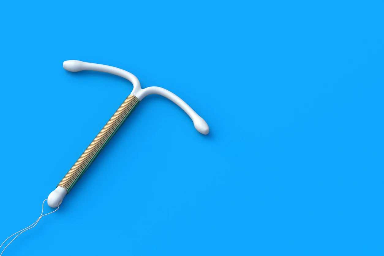 An image of a copper IUD against a blue device highlighting complications and injury claims involving copper IUD contraceptive devices litigated by Trident Law HQ
