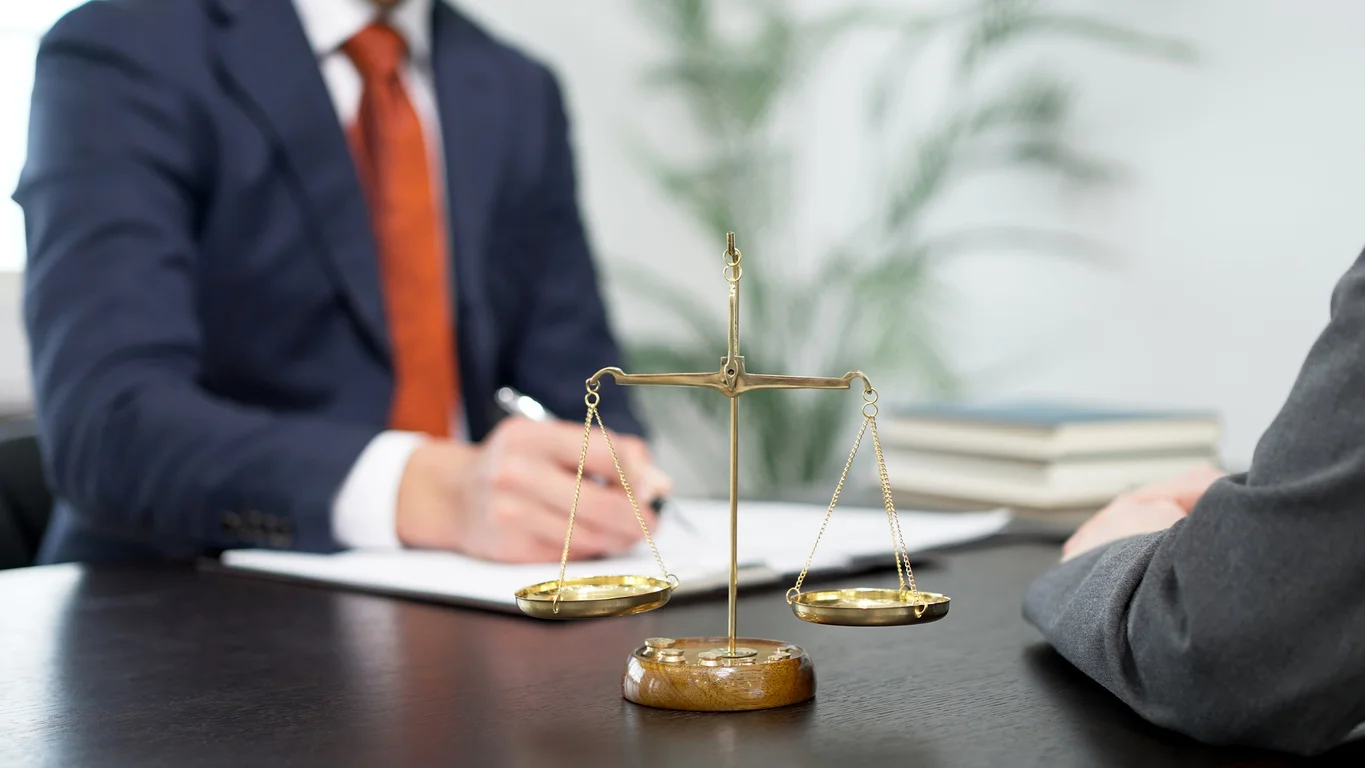 an image of a man's hands signing documents on a desk next to a gavel to represent attorneys at Trident Law HQ