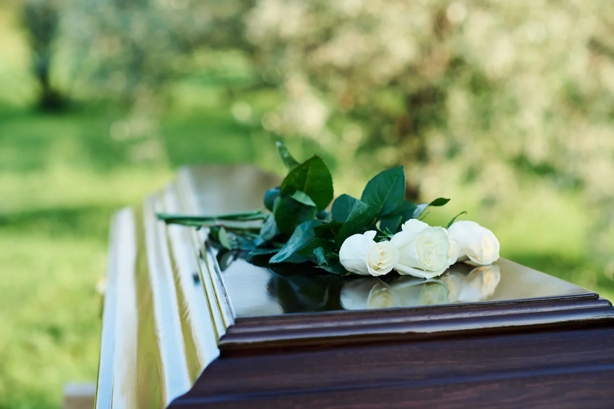 White roses on wooden coffin symbolizing wrongful death cases supported by Trident Law HQ